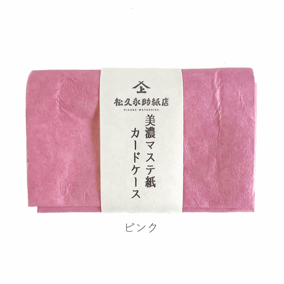 美濃和紙のマスキングテープ原紙を使った、カードケースのピンク色がうつっています。中央には、店名、商品名が記載された商品帯が縦にまかれています。下記は関連するキーワードになります。和紙 カードケース 名刺入れ 美濃和紙 マスキングテープ 原紙 アップサイクル 環境に優しい 経年変化 ハンドメイド ピンク 推しカラー パステルカラー かわいい 松久永助紙店 オンラインショップ