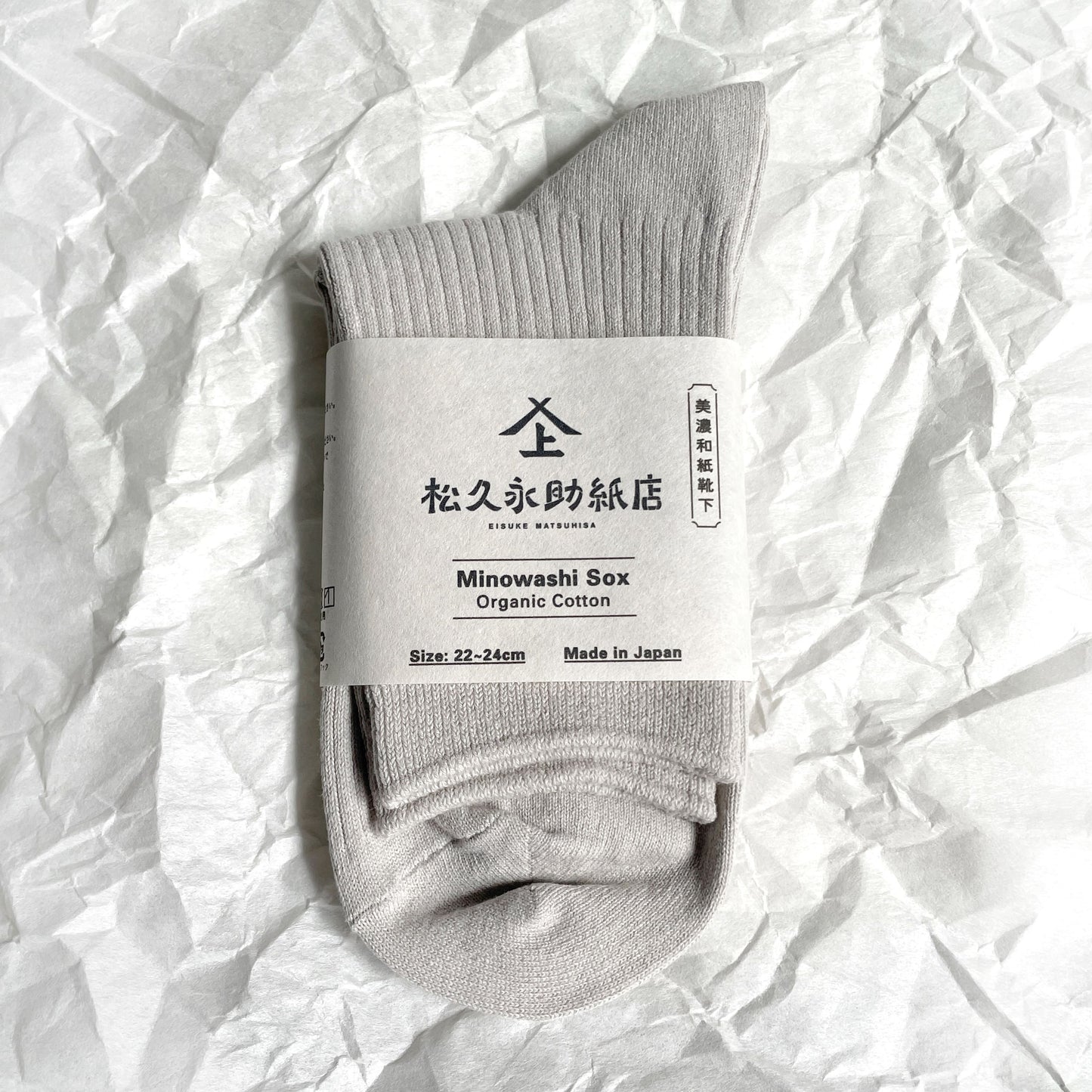 美濃和紙靴下(新仕様)、ベーシックタイプ、22-24cm、グレーが1足、半分に折りたたまれた状態でうつっています。店名、商品名、サイズ、日本製である旨が記載された商品帯が商品の真ん中にまかれています。下記は関連するキーワードになります。靴下 ソックス 和紙製品 美濃和紙 こだわり 機能的 おすすめ ムレない 消臭 抗菌 健康対策 エコ プレゼント 母の日 父の日 敬老の日 おすすめ 人気 松久永助紙店 オンラインショップ