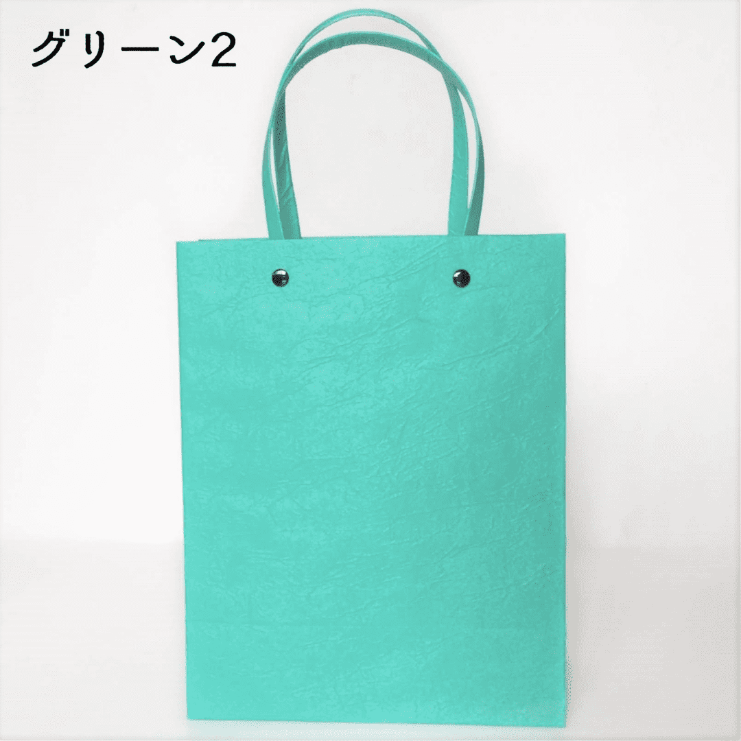 美濃和紙のマスキングテープ原紙を使った、手提げバッグの淡い緑色がうつっています。持ち手と本体を固定する(繋ぐ)金具は黒です。下記は関連するキーワードになります。美濃和紙 和紙 マスキングテープ 原紙 手作り ハンドメイド 紙カバン 和小物 和装 シンプル 合わせやすい 緑 推しカラー パステルカラー 松久永助紙店 オンラインショップ