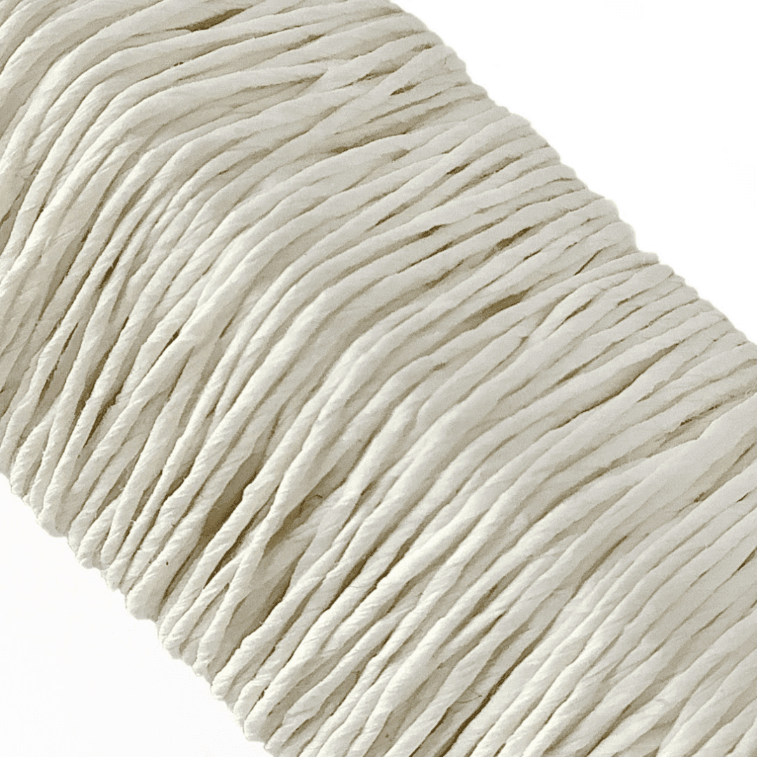 白い背景に、Kamito糸柱の白（染なし）がうつっています。糸や色の風合いがわかるようアップで撮影された写真です。原料内訳は美濃和紙100％です。下記は関連するキーワードになります。紙糸 和紙糸 草木染め オリジナル 機械漉き 美濃和紙 自然素材 天然繊維 エコ サスティナブル 環境に優しい 人に優しい ハンドメイド クラフト 材料 素材 ラッピング アクセサリー作り 小物づくり タッセル ニット 編み物 刺繍 生成り色 和紙色 ナチュラル 作品 アート 販売 松久永助紙店 オンラインショップ