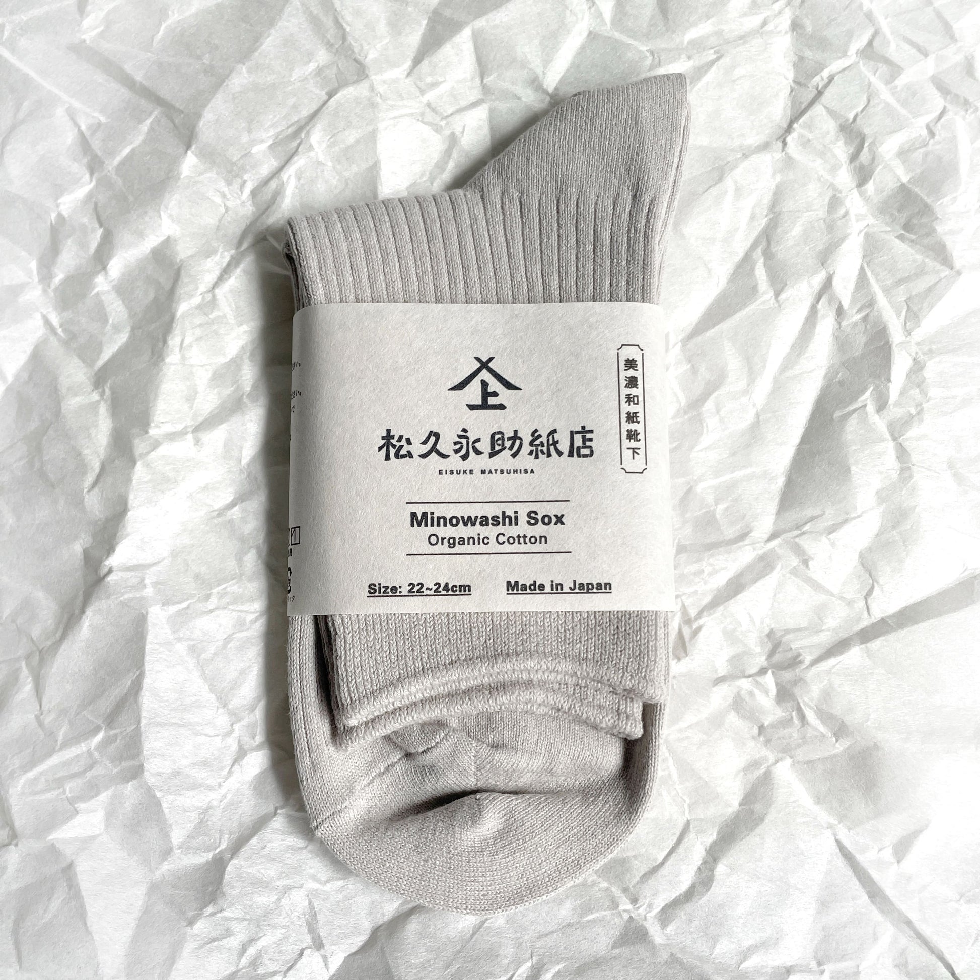 美濃和紙靴下（新仕様）、ベーシックタイプ、22-24cm、グレーが1足、半分に折りたたまれた状態でうつっています。店名、商品名、サイズ、日本製である旨が記載された商品帯が商品の真ん中にまかれています。下記は関連するキーワードになります。靴下 ソックス 和紙製品 美濃和紙 こだわり 機能的 おすすめ ムレない 消臭 抗菌 健康対策 エコ プレゼント 母の日 父の日 敬老の日 おすすめ 人気 松久永助紙店 オンラインショップ
