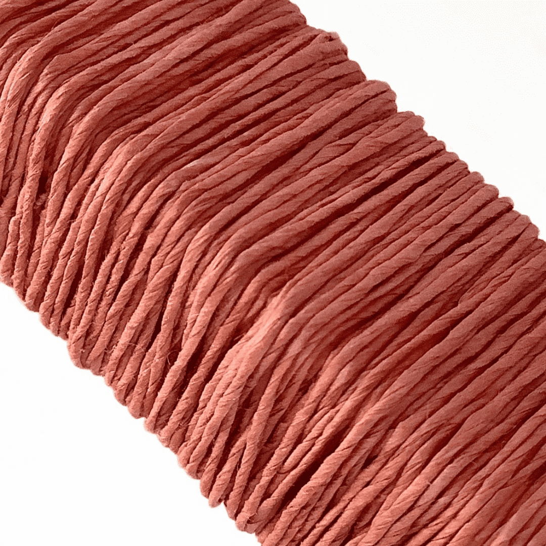 白い背景に、Kamito糸柱の赤（茜）がうつっています。糸や色の風合いがわかるようアップで撮影された写真です。原料内訳は美濃和紙100％です。下記は関連するキーワードになります。紙糸 和紙糸 草木染め オリジナル 機械漉き 美濃和紙 自然素材 天然繊維 エコ サスティナブル 環境に優しい 人に優しい ハンドメイド クラフト 材料 素材 ラッピング アクセサリー作り 小物づくり タッセル ニット 編み物 刺繍 茜色 赤 茜染め あるだけ ナチュラル 自然 販売 松久永助紙店 オンラインショップ