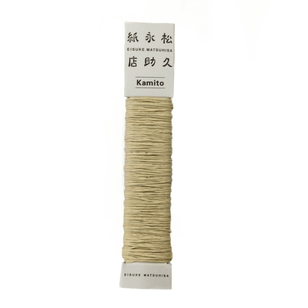 白い背景に、Kamito糸柱の黄（キハダ）が置かれています。全体像が分かるよう撮影された写真です。糸は店名、商品名が記載された、紙の柱のようなパッケージにまかれています。原料内訳は美濃和紙100％です。下記は関連するキーワードになります。紙糸 和紙糸 草木染め オリジナル 機械漉き 美濃和紙 自然素材 天然繊維 エコ サスティナブル 環境に優しい 人に優しい ハンドメイド クラフト 材料 素材 ラッピング アクセサリー作り 小物づくり タッセル ニット 編み物 刺繍 黄色 キハダ染め 販売 松久永助紙店 オンラインショップ